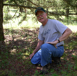 harlie Conner inspects sprouted seedling under tree